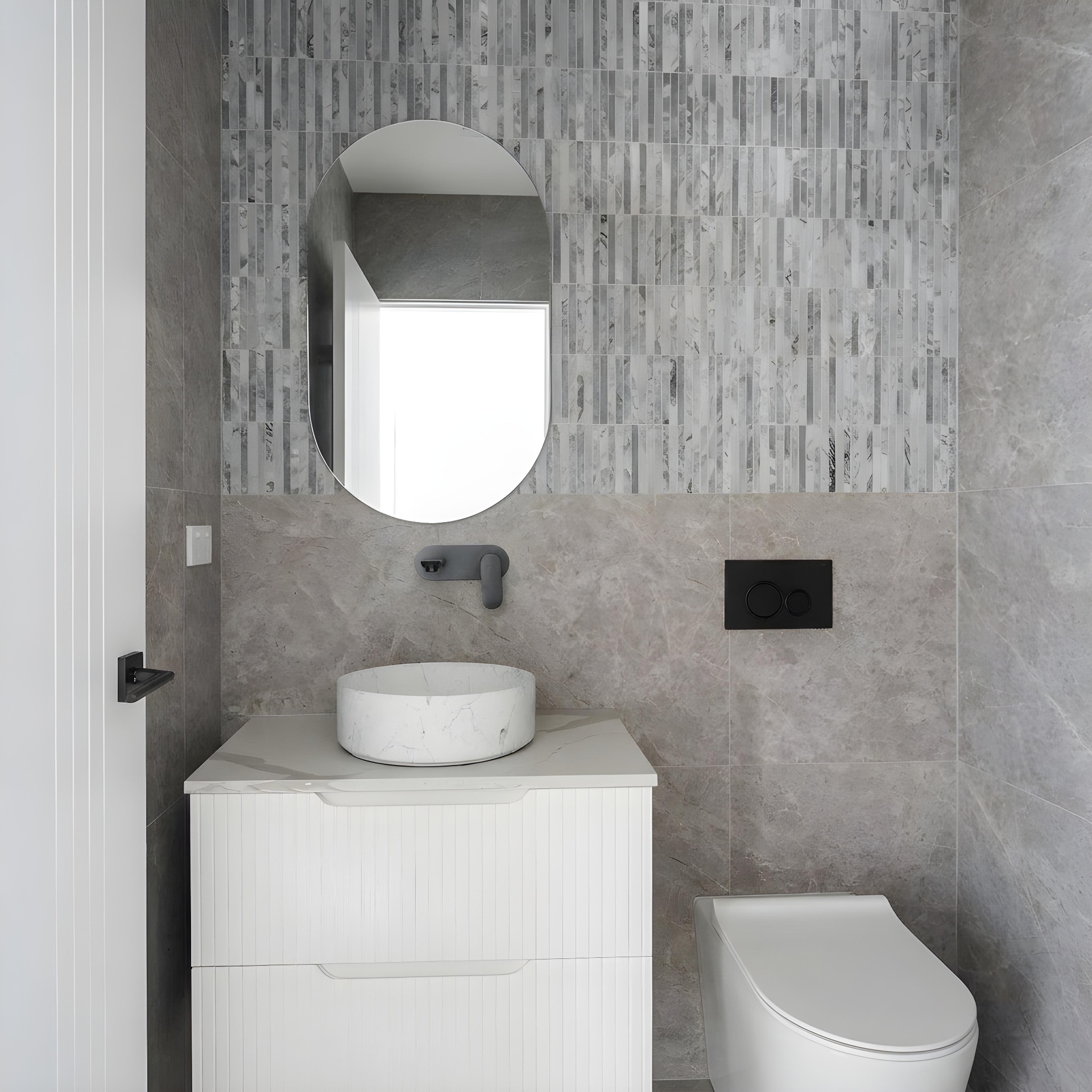 Powder room with patterned grey marble feature wall, oval mirror and stone vessel basin